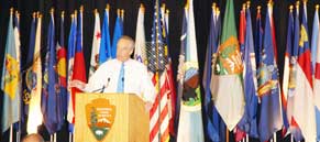 Interior Secretary Dick Kempthorne Speaking in front of a back drop of Flags